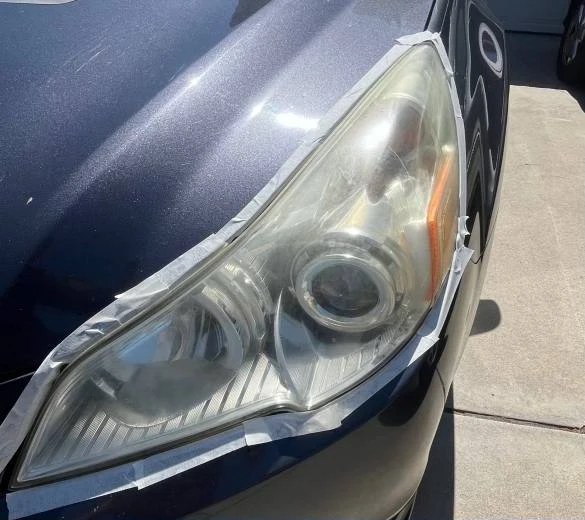 Before: yellowed, oxidized headlight lens on a customer car in Oceanside, taped off for restoration